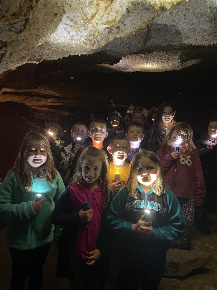 a group of student in a dark cave holding flashlights
