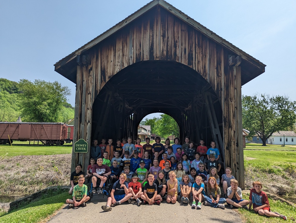 4th graders sit under a covered bridge at Stonefield