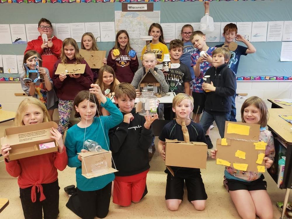 a group of students are holding their inventions made out of recycled products