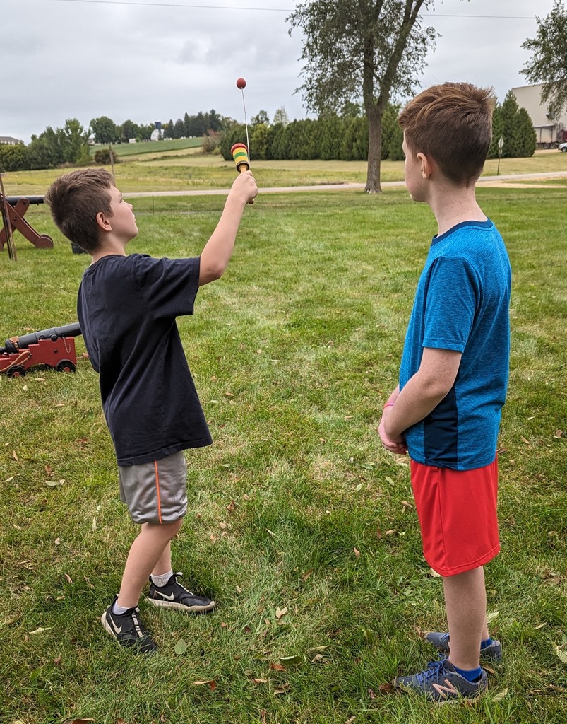 students try their hand at a colonial game with a small ball with string and little basket