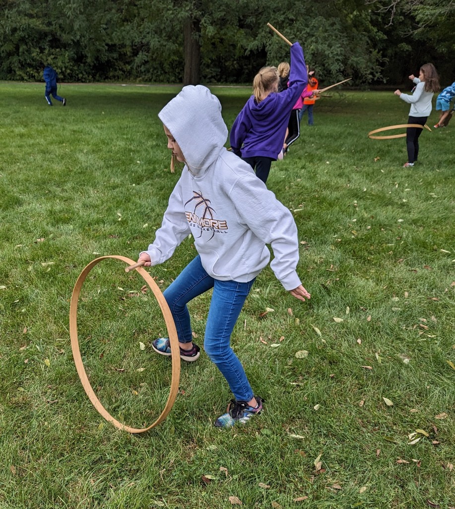 students play different colonial games outside with wooden hoops and sticks