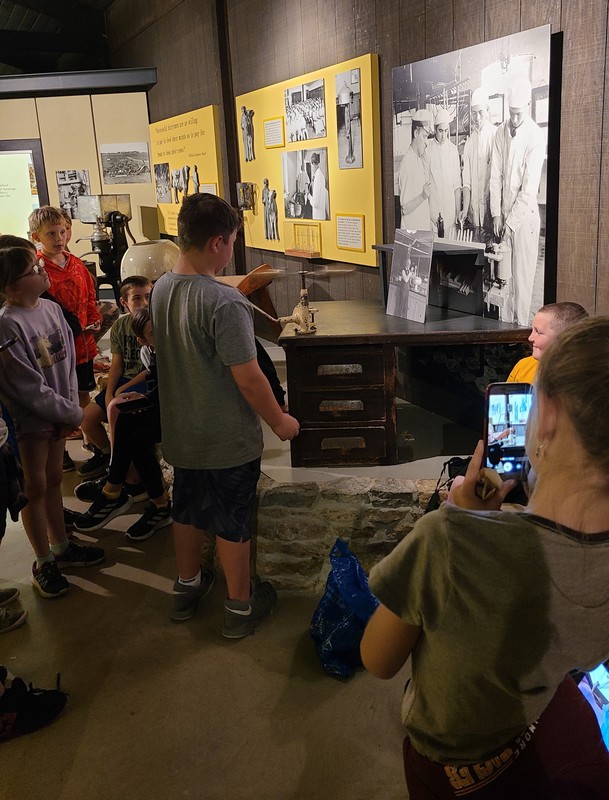a group of students view an exhibit at Stonefield village