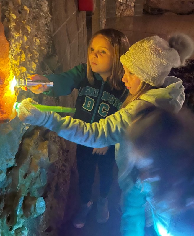 2 students explore a cave with flashlights