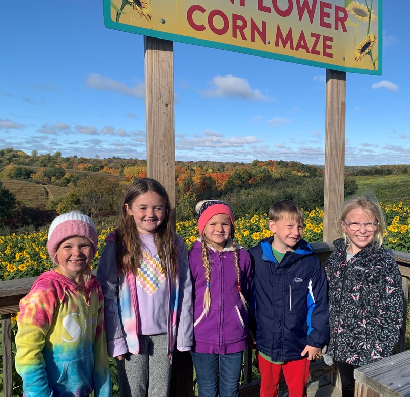 5 students Stand in front of sunflower corn maze sign